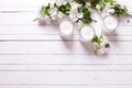 Apple tree flowers and three candles on white wooden background