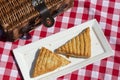 Apple turnover on a white plate, with a wicker picnic basket,  outdoors in sunshine. on a gingham cloth. Royalty Free Stock Photo