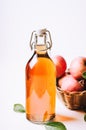 Apple vinegar in a bottle on white wooden table with apples in a basket. Royalty Free Stock Photo