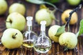 Apple vinegar in glass jar with ripe green fruit. Bottle of apple organic vinegar on wooden background. Healthy organic food.