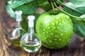 Apple vinegar in glass jar with ripe green fruit. Bottle of apple organic vinegar on wooden background. Healthy organic food.