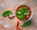 Apple vitamin drink with small ranetki and green basil leaves in a large glass