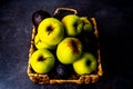 Apples and avocados in wicker platter on black surface Royalty Free Stock Photo