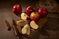 Apples board. Apples and a knife are on a cutting board and one apple is cut into four pieces and the whole composition on a dark