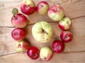 Apples in a circle and in the middle an apple on a wooden table Royalty Free Stock Photo