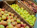Apples of different varieties lie in a wicker box on a grocery shelf. Close-up of fruit in a supermarket. Fresh apples Royalty Free Stock Photo
