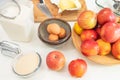 Apples, eggs, sugar, butter, flour, and some ingredients close up on a kitchen table