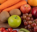 Apples, grapes, carrots and oranges placed together on the ground