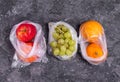 Apples, grapes and oranges in plastic bags on a dark background Royalty Free Stock Photo