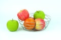 Apples and oranges in a decoratively wire basket put on isolated white background and there is an apple outside the wire basket. Royalty Free Stock Photo