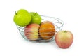 Apples and oranges in a decoratively wire basket put on isolated white background and there is an apple outside the wire basket. Royalty Free Stock Photo