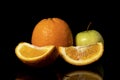 Apples and oranges fruits with drops and splashes of water on a black background Royalty Free Stock Photo