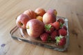 Apples, peaches and strawberries on on glass serving plate on the wooden table close up