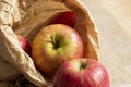 Apples, Pink Lady variety, in a brown paper bag on a wood background. Environmentally friendly packaging concep