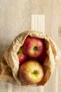 Apples, Pink Lady variety, in a brown paper bag on a wood background. Environmentally friendly packaging concep