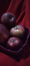 apples in a purple bamboo basket with a red background