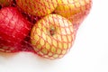 Apples in a red net. ECO Shopping - apples in the net. Apples are yellow with red in one grid on a white table Royalty Free Stock Photo