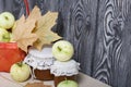 Apples in a red wicker basket. Jam in jars, apples and dried maple leaves are nearby. Fruit harvest Royalty Free Stock Photo