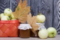 Apples in a red wicker basket. Jam in jars, apples and dried maple leaves are nearby. Fruit harvest Royalty Free Stock Photo