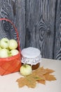 Apples in a red wicker basket. Jam in jars, apples and the highest maple leaves are nearby. Fruit harvest Royalty Free Stock Photo