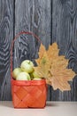 Apples in a red wicker basket. Nearby are dried maple leaves. Fruit harvest Royalty Free Stock Photo