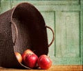 Apples spilling out of basket on grunge background Royalty Free Stock Photo