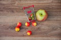 Apples, strawberries and small shopping cart on table