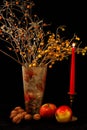 Apples ,walnuts ,glass of wine and vase of flowers on black background