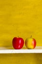 Apples on white shelve yellow wall background.