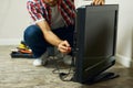 Appliance service. Cropped shot of repairman using a screwdriver while installing or fixing tv set indoors