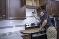 Appliance technician drilling under a cabinet