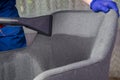 Application of water with a cleaning solution for further cleaning of the gray chair, professional cleaning of upholstered