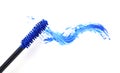 Applicator and blue mascara smear on white background, top view