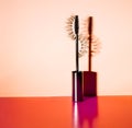 Applicator mascara and false eyelashes with drop shadow on orange background