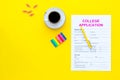 Apply college. Empty college application form near coffee cup and stationery on yellow background top view copy space
