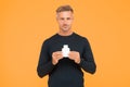 Apply fragrance on your skin. Handsome man hold perfume bottle yellow background. Mens grooming. Skin cosmetics