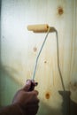 Applying clear coat paint on a wooden surface with roller brush. Painting wood wall and floor Royalty Free Stock Photo