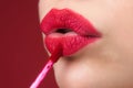 Applying lipstick, macro. Painting lips with bright lipstick, close up. Pampering, lips correction concept. Glossy