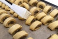 Applying oil to freshly made, raw yeast dough patties with mushrooms inside, using a silicone cooking trowel.