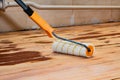 Applying primer on old wooden floor using roller. Royalty Free Stock Photo