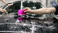 Smoothing the protective film on the car. The worker-detailer smoothes the protective film with the help of a working