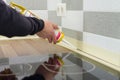 Applying silicone sealant with construction syringe. Worker fills seam between the ceramic tiles on the wall and kitchen worktop