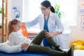 Blonde kid lying on a daybed while doctor observing her hurting leg
