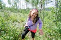 Apprehensive woman gives unsure, cautious look as she emerges from a hike in the woods. Carrying DSLR Camera