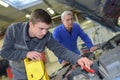 apprentice mechanic in auto shop working on car engine Royalty Free Stock Photo