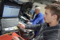 Apprentice mechanic diagnosing car problem with computer Royalty Free Stock Photo