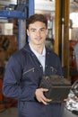 Apprentice Mechanic Holding Car Battery In Auto Repair Shop