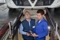 Apprentice mechanic repairing car monitored by mentor