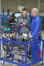 Apprentice mechanic working on engine block with senior teacher Royalty Free Stock Photo