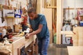 Apprentice Planing Wood In Carpentry Workshop